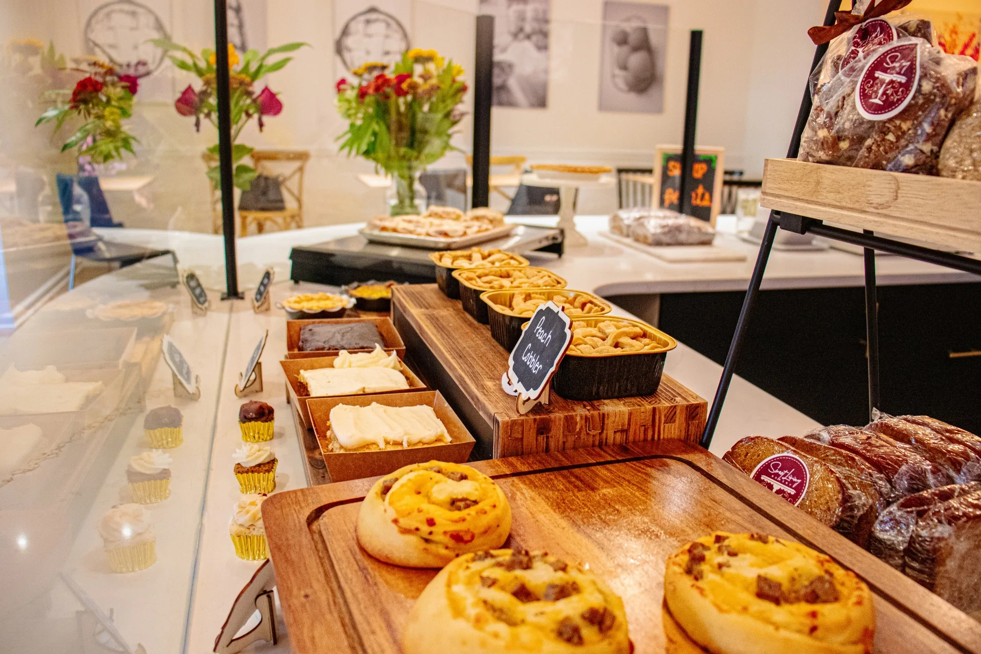 A variety of freshly baked goods displayed in a bakery case with a staff member in the background.